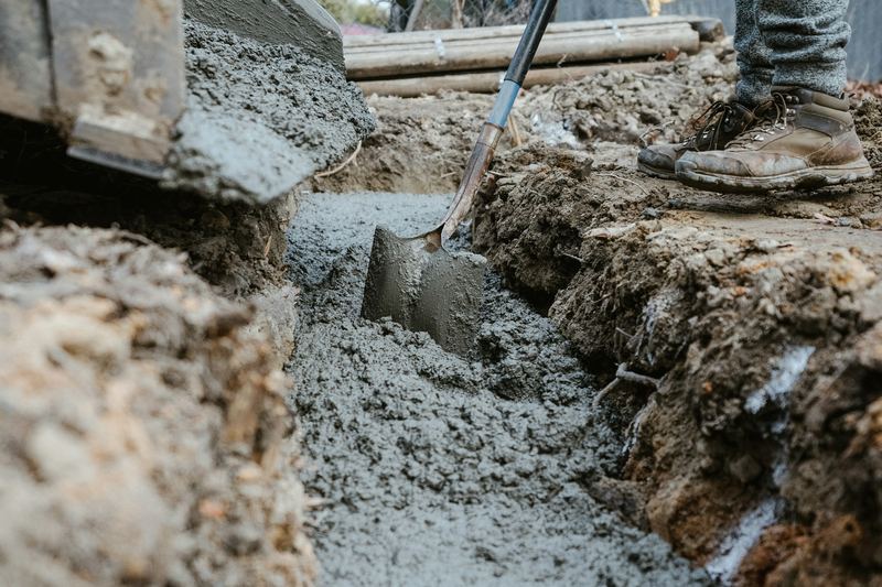 Person digging a narrow drainage trench by hand